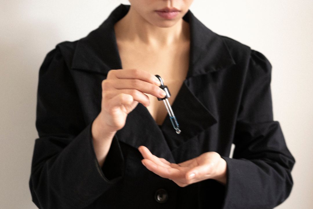 Nainen kädessään pipetillinen seerumia