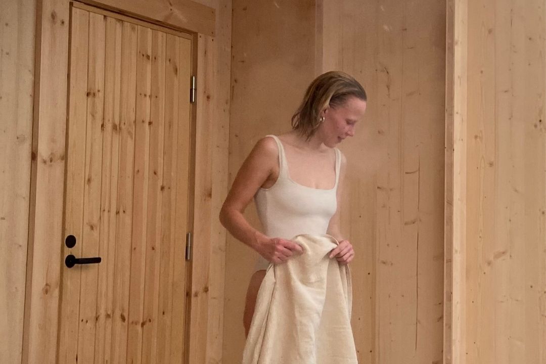 Nainen pyyhe kädessä saunan ulkopuolella