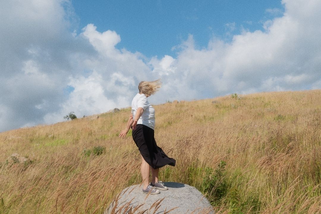 Nainen syksyisellä, tuulisella niityllä